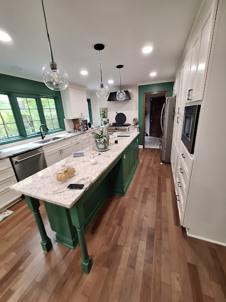 A kitchen with green cabinets and a marble island