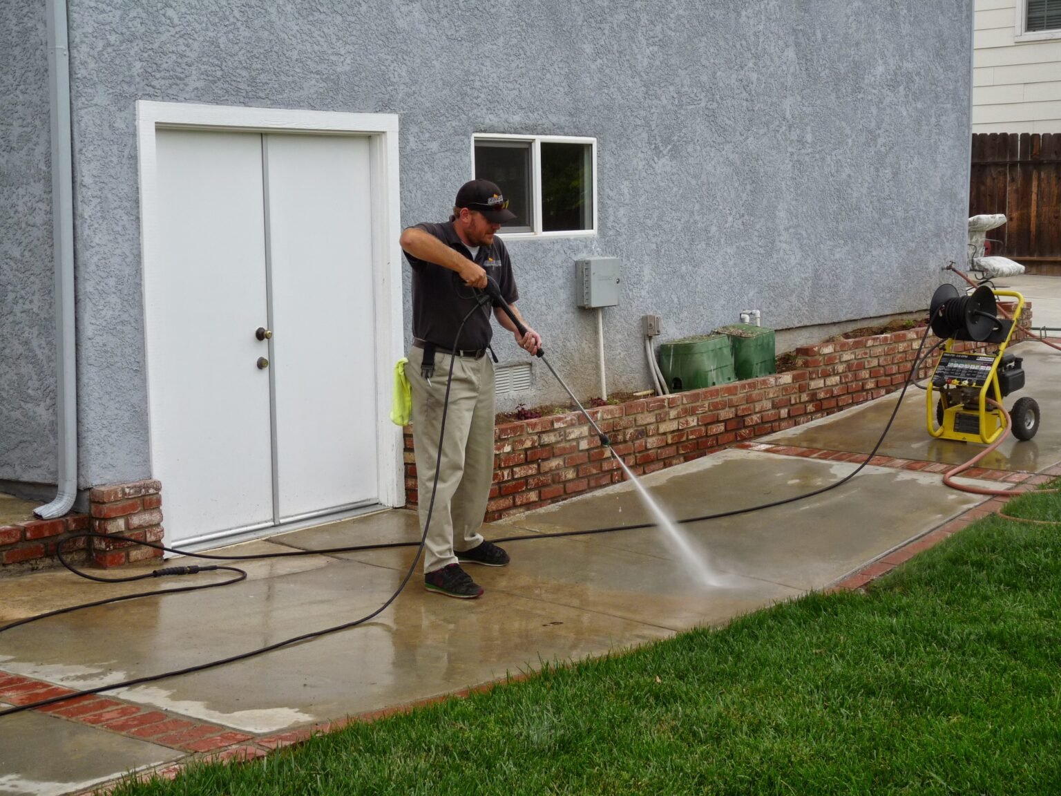 A man using a pressure washer on a driveway