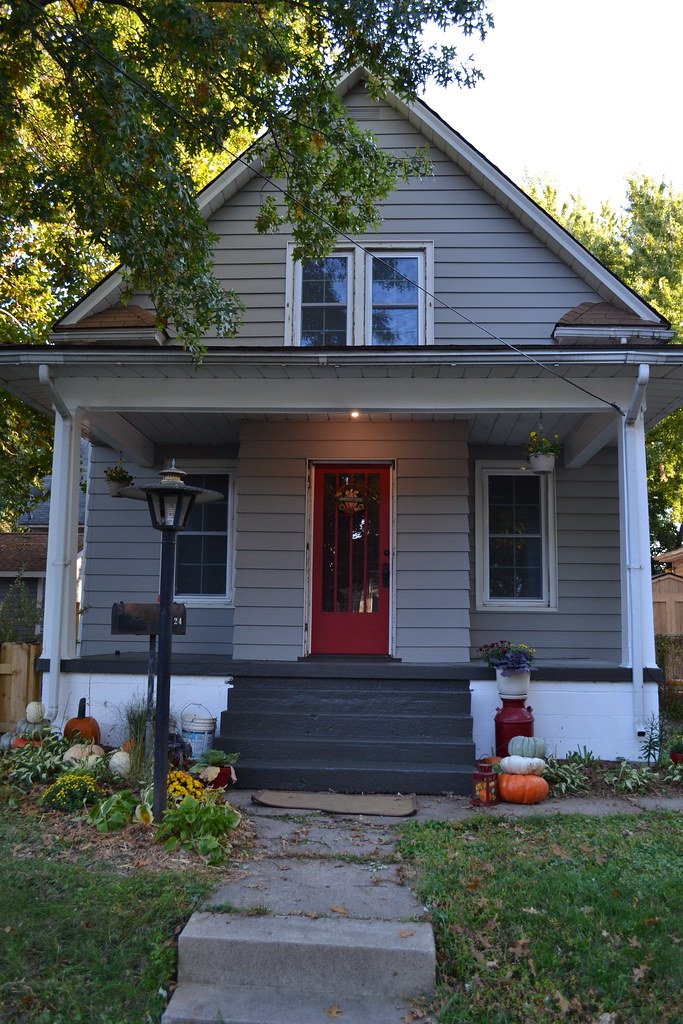 A gray house with a red door and a red front door