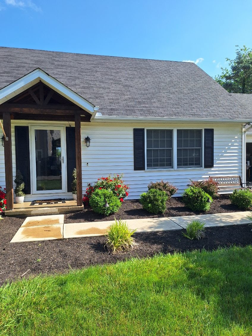 A white house with black shutters and landscaping